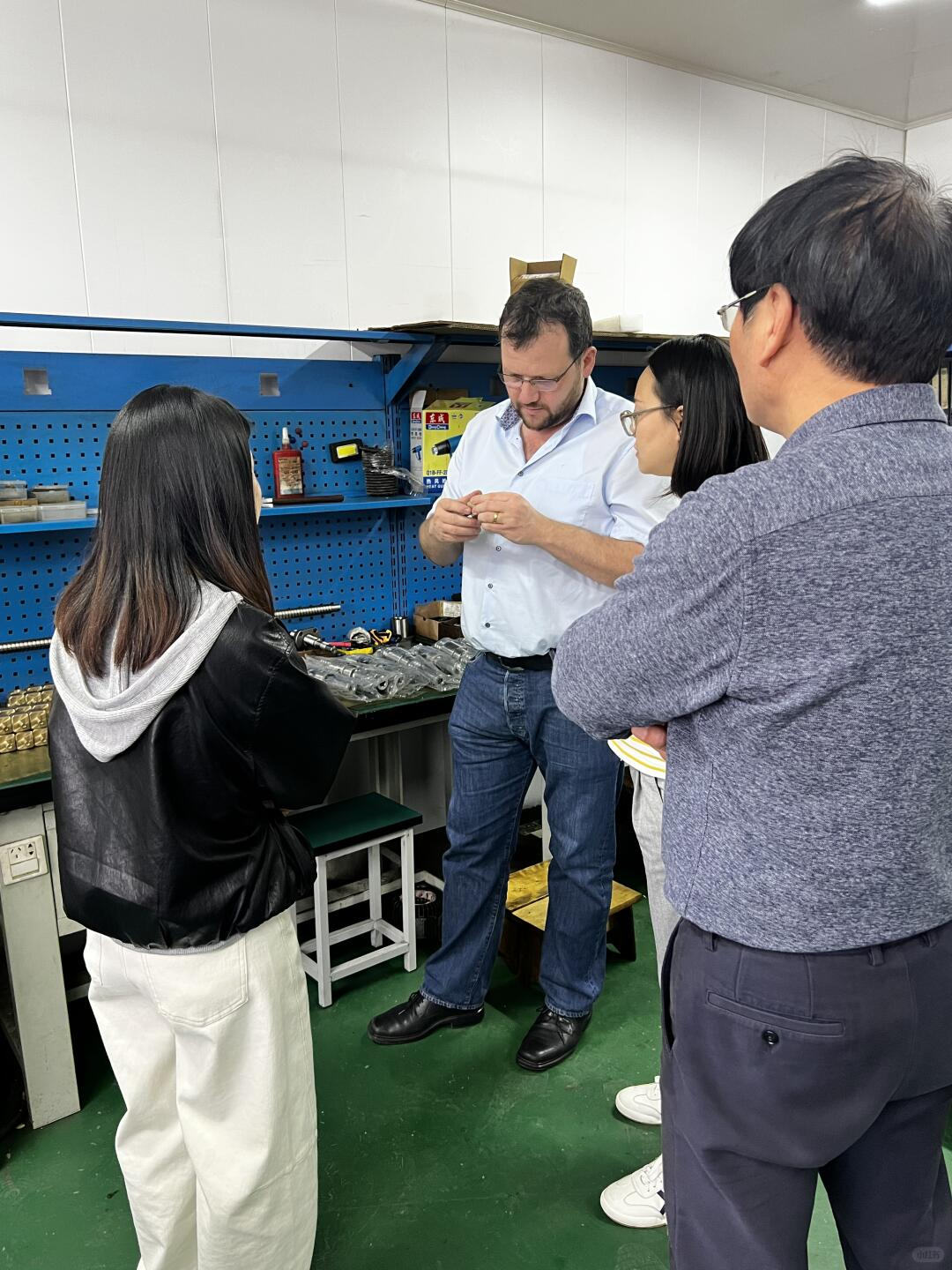Factory visit group reviewing prototype hardware parts